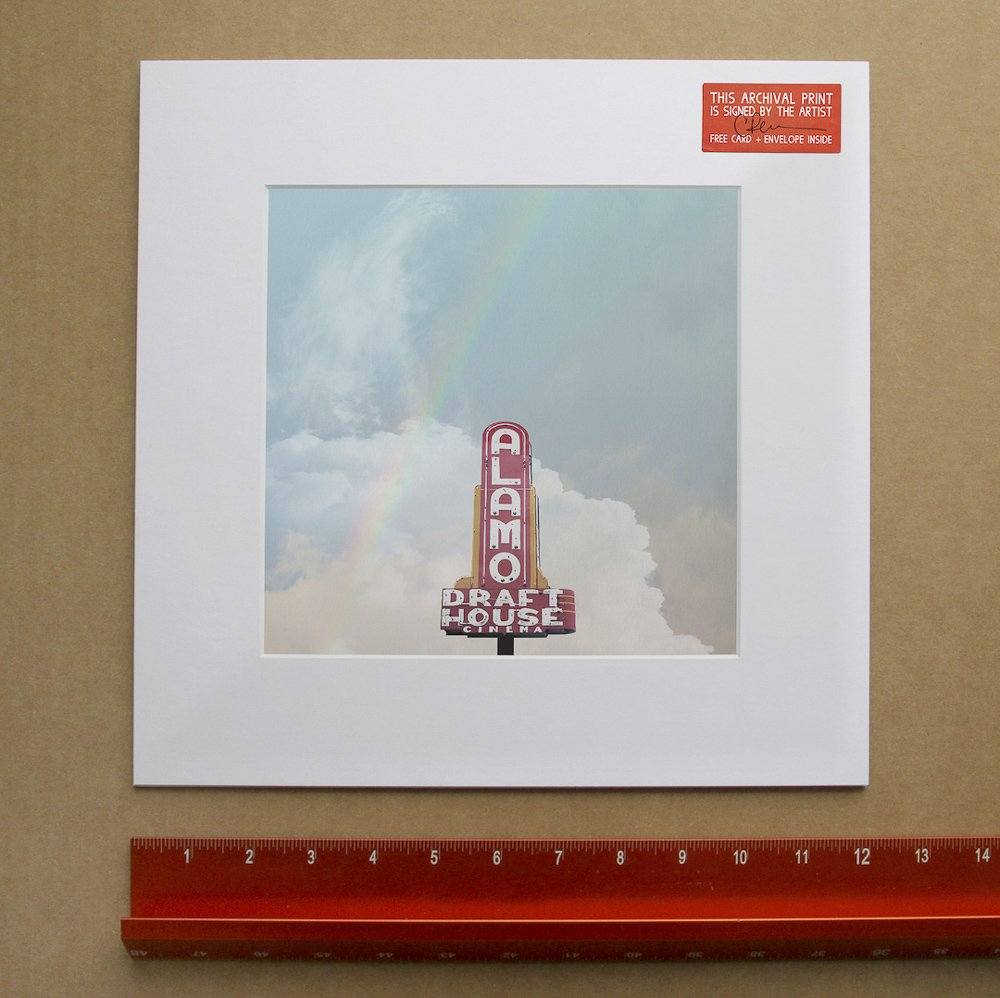 Alamo Drafthouse Austin Art print featuring vintage movie theater sign with rainbow and cloudy sky, signed by artist Betsy Crum