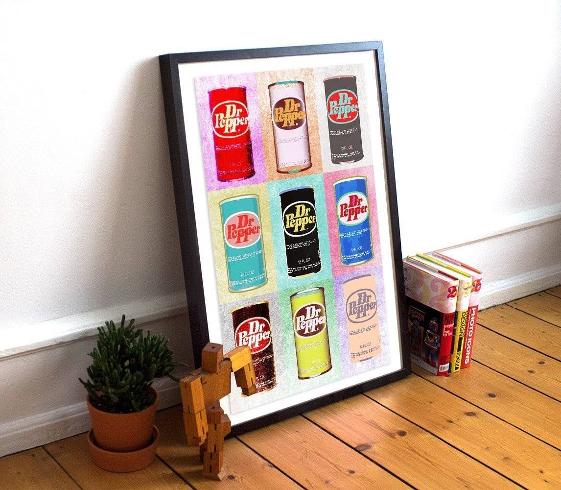 Framed Dr. Pepper Warhol Style print featuring nine colorful soda cans on heavyweight acid-free paper displayed on wooden floor next to plant and books