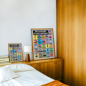 Alphabet of San Antonio art print by Betsy Crum — framed in a wood-accent room