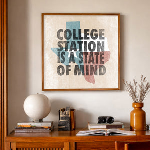 College Station State of Mind art print in a mid-century room — bold letterpress type over a weathered Texas flag by Betsy Crum. Square Brazos Valley wall art, printed in Texas.