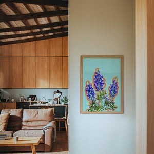 Blue Hill Country bluebonnet art print by Betsy Crum — framed in a wood-accent room
