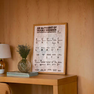 Alphabet of Texas Women Texas Art print by Caya Crum — framed in a wood-accent room