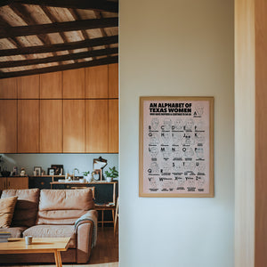 Alphabet of Texas Women Texas Art print by Caya Crum — framed in a wood-accent room