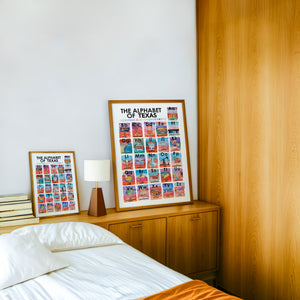 Alphabet of Texas Icons Texas Art print by Caya Crum — framed in a wood-accent room