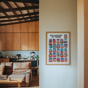 Alphabet of Texas Icons Texas Art print by Caya Crum — framed in a wood-accent room