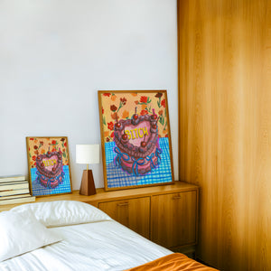 Bitch Cake pink wall art print by Caya Crum — framed in a wood-accent room