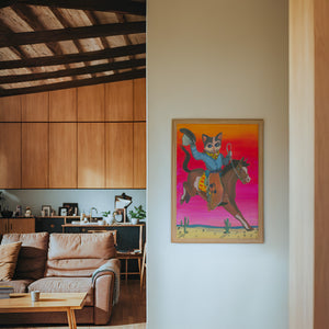 Cat Cowboy Bronco cat art print by Caya Crum — framed in a wood-accent room