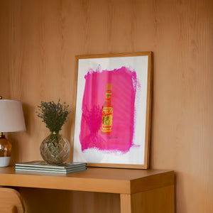 Cholula Hot Sauce kitchen art print by Caya Crum — framed in a wood-accent room