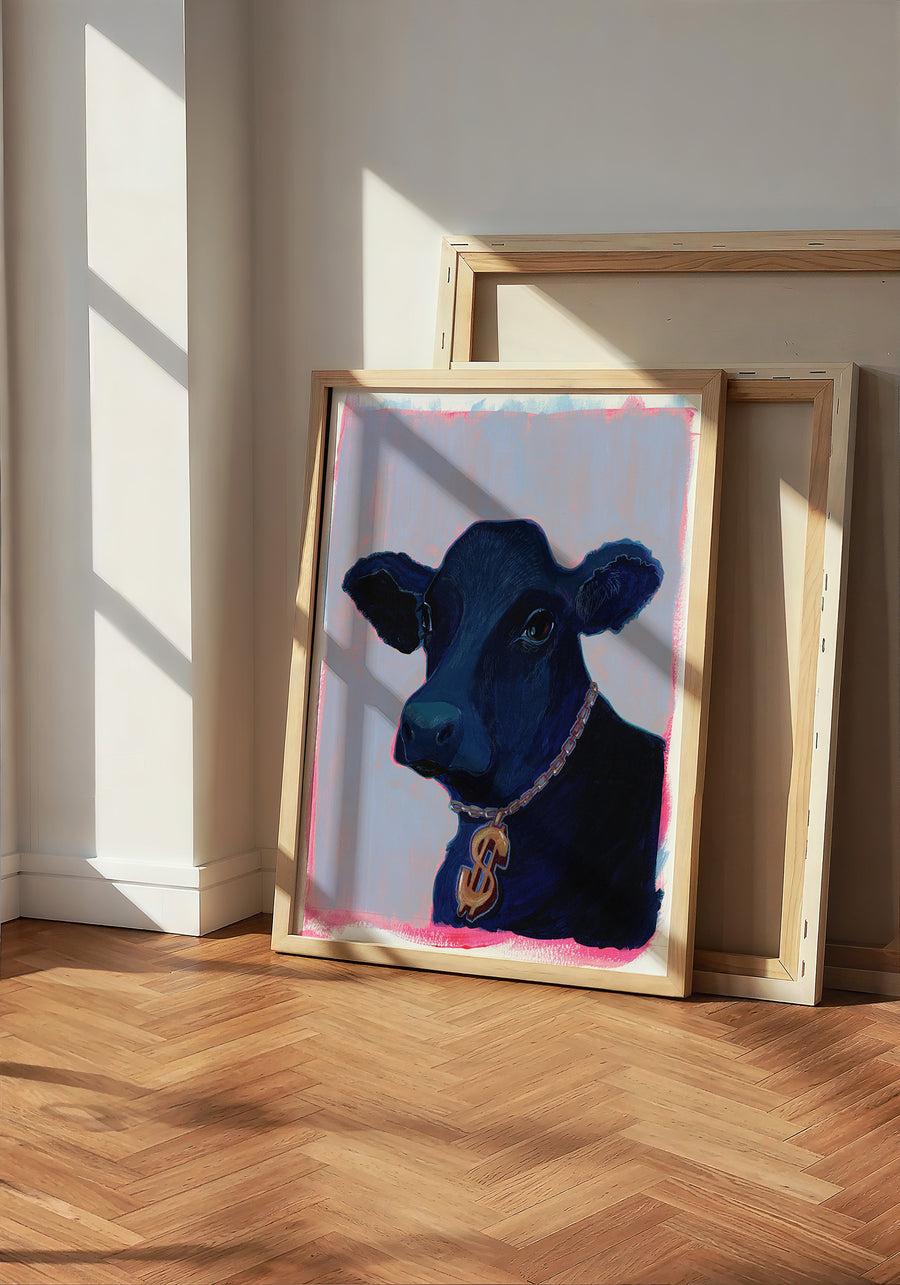 Money Cow, a pop-art cow print by Caya Crum, framed and leaning against a sunlit wall in the Crum Art studio