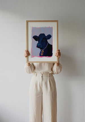 Money Cow black cow art print with dollar-sign charm by Caya Crum — framed vertical room scene