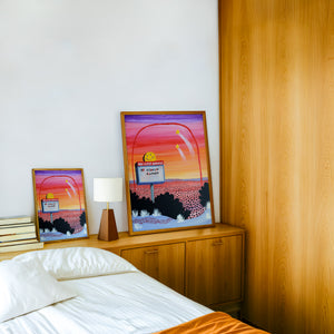 No A-Holes Neon Desert weirdcore print by Caya Crum — framed in a wood-accent room