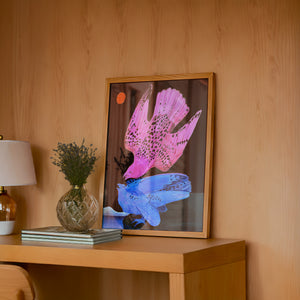 Pink & Blue Birds at Night bird art print by Caya Crum — framed in a wood-accent room