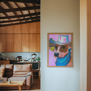 Hazel cow art print by Caya Crum — framed in a wood-accent room