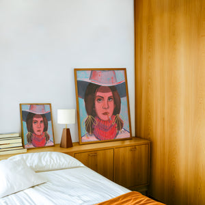 Lana cowgirl art print by Caya Crum — framed in a wood-accent room