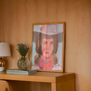 Lana cowgirl art print by Caya Crum — framed in a wood-accent room