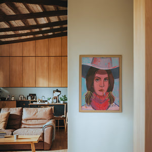 Lana cowgirl art print by Caya Crum — framed in a wood-accent room