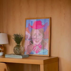 Hanna cowgirl art print by Caya Crum — framed in a wood-accent room