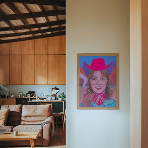 Hanna cowgirl art print by Caya Crum — framed in a wood-accent room