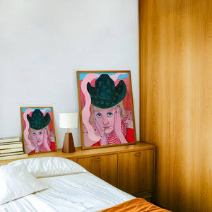 Emma cowgirl art print by Caya Crum — framed in a wood-accent room