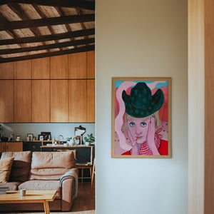 Emma cowgirl art print by Caya Crum — framed in a wood-accent room