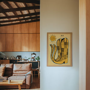 Roach Stompers cowboy boot art print by Caya Crum — framed in a wood-accent room
