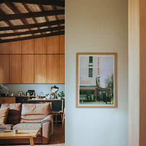 Zabar's NYC art print by Caya Crum — framed in a wood-accent room
