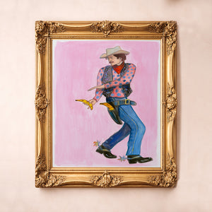 Banana Guns cowboy art print in a gold frame by Caya Crum — a pink western painting of a cowboy drawing bananas, available at crumart.com. This museum quality print is made right here in Texas.