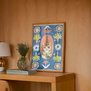 Party Cat Poppett cat art print by Caya Crum — framed in a wood-accent room