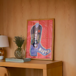 Justin Boot cowboy boot art print by Caya Crum — framed in a wood-accent room