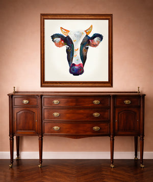 Watercolor cow portrait print by Caya Crum framed in a western styled room