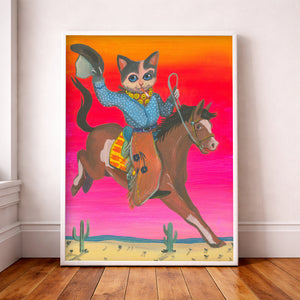 Cowboy Cat Art Print in a white frame on a neutral wall.  This Cat is a Smoking Bronc Buster and a Maximalist wall art statement piece.  24x36" Cat Art Print by Caya Crum