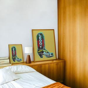 Leddy Boot Ochre cowboy boot art print by Betsy Crum — framed in a wood-accent room