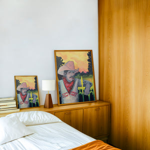 Howdy Rowdy cowboy art print by Caya Crum — framed in a wood-accent room