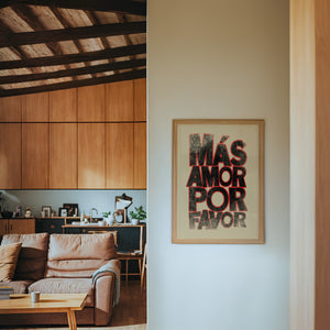 Mas Amor Por Favor typography print by Betsy Crum — framed in a wood-accent room