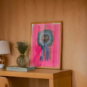 Slay Ribbon funny wall art print by Caya Crum — framed in a wood-accent room