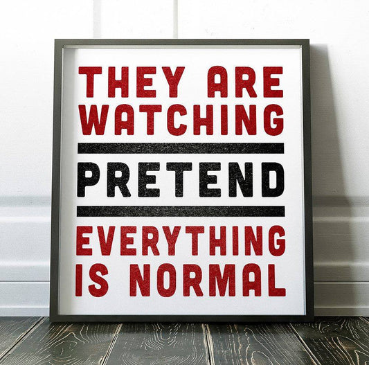 Framed museum print with bold red and black text reading "They Are Watching Pretend Everything Is Normal" on white background