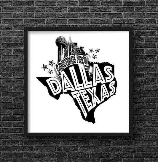Black and white Greetings From Dallas Texas art print by Betsy Crum in a black frame on brick wall