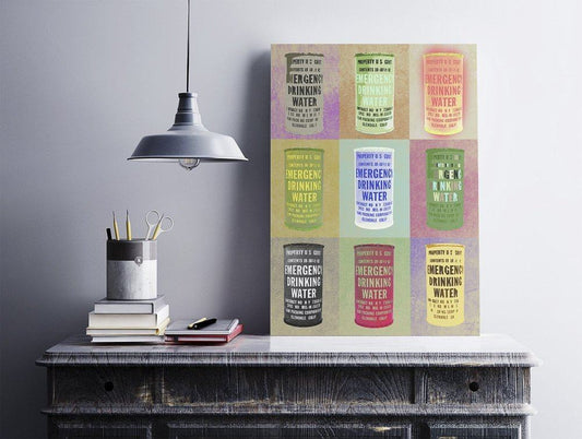 Colorful museum print featuring nine vintage-style Emergency Drinking Water cans on 100% acid-free cotton paper displayed on a wooden table under a hanging lamp.