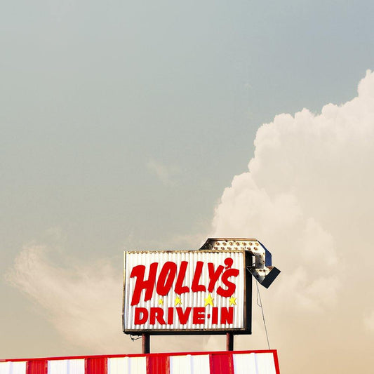 Vintage Holly's Drive In sign in Post, Texas with red lettering on a white background and a blue sky backdrop