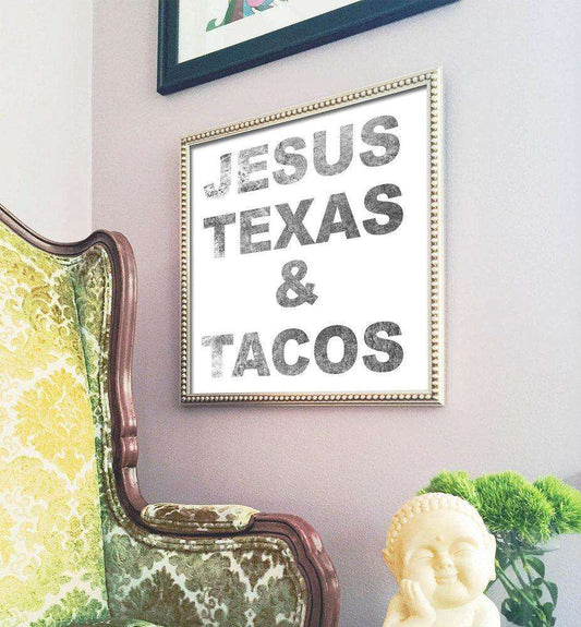 Jesus Texas & Tacos black text art print in decorative frame on wall next to vintage chair and plant