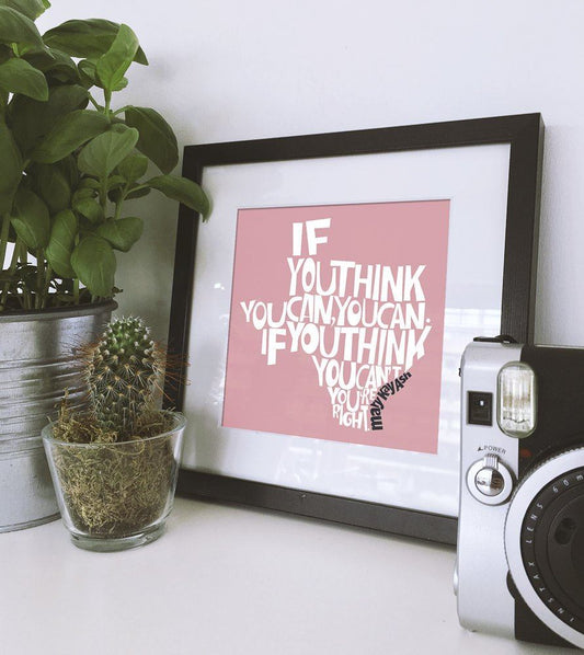 Museum print featuring Mary Kay Ash quote in black frame displayed next to potted plants and camera