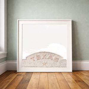 Marfa Texas sign print by Betsy Crum framed upright against a grey-green wall