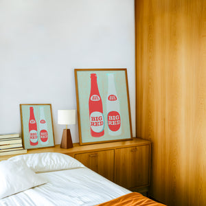 Big Red Two Bottles kitchen print by Betsy Crum — framed in a wood-accent room