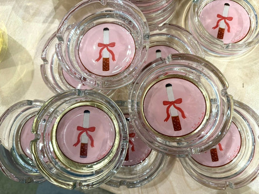 Cigarette with a Bow glass ashtrays by Tavi Crum for Crum Art, pink with a red ribbon bow and gold ring, seen from above