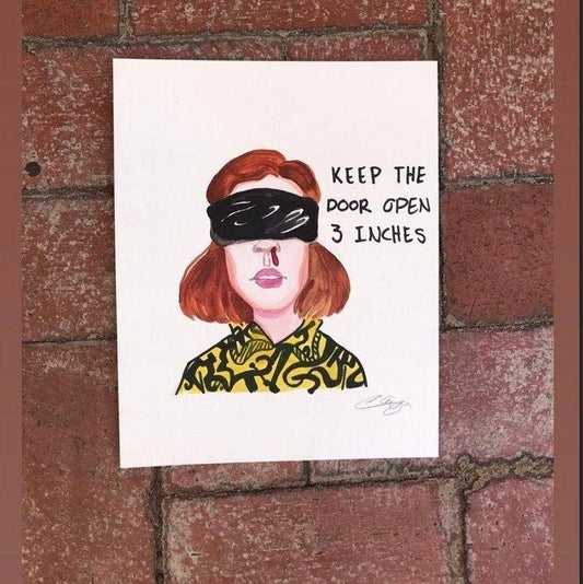 Stranger Things fan art print featuring a red-haired character with a blindfold and text "KEEP THE DOOR OPEN 3 INCHES" on white paper against a brick background.