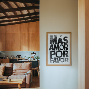 Mas Amor Por Favor typography print by Betsy Crum — framed in a wood-accent room