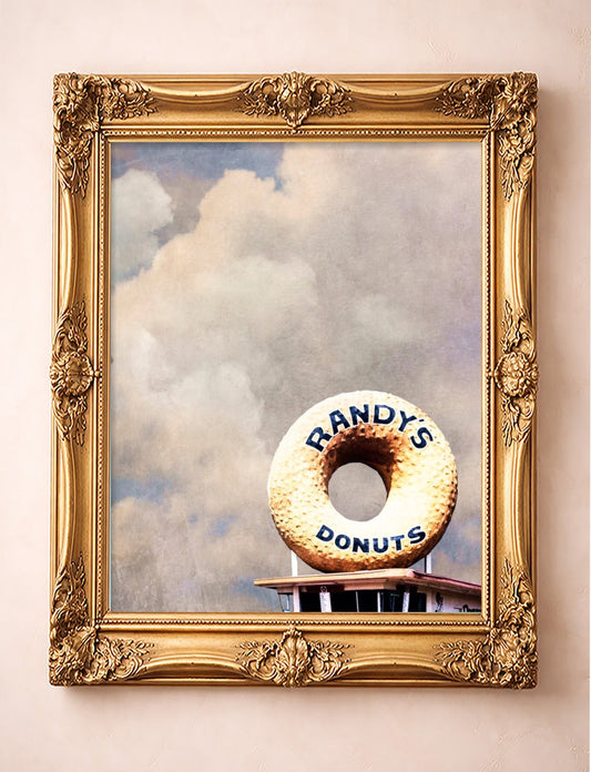 Randy's Donuts Los Angeles art print by Betsy Crum in a vertical gold frame, the giant donut sign under a big cloudy sky
