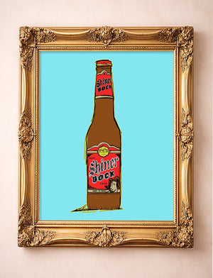 Shiner Bock beer bottle pop art print by Betsy Crum in a gold frame, Texas bar art on a blue sky background